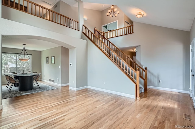 5784 W 81st Cir, Arvada, CO 80003 - unfurnished living room featuring arched walkways, wood finished floors, stairway, baseboards, and a towering ceiling