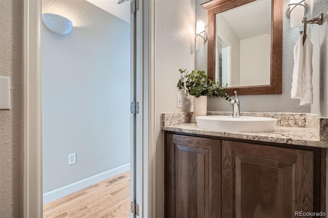 5784 W 81st Cir, Arvada, CO 80003 - bathroom with wood finished floors, vanity, baseboards, and a textured wall