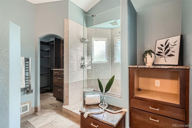 5784 W 81st Cir, Arvada, CO 80003 - bathroom featuring a tile shower, a spacious closet, and vaulted ceiling