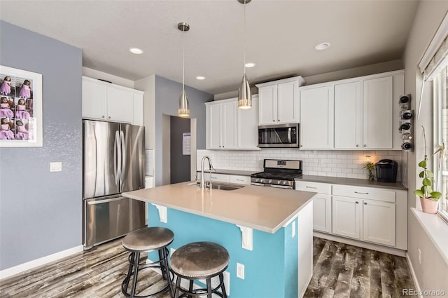 kitchen featuring white cabinetry, hanging light fixtures, stainless steel appliances, dark hardwood / wood-style floors, and an island with sink