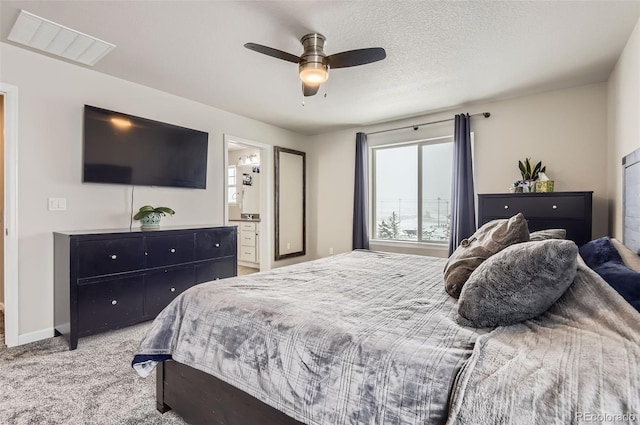 bedroom featuring ensuite bath, ceiling fan, light carpet, and a textured ceiling