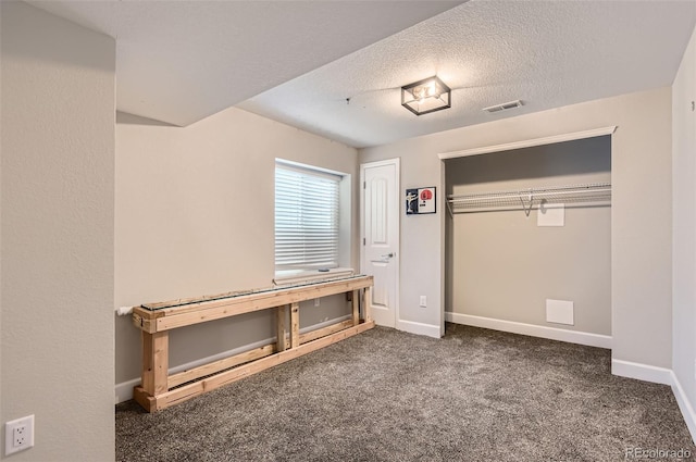 unfurnished bedroom featuring dark carpet, a textured ceiling, and a closet