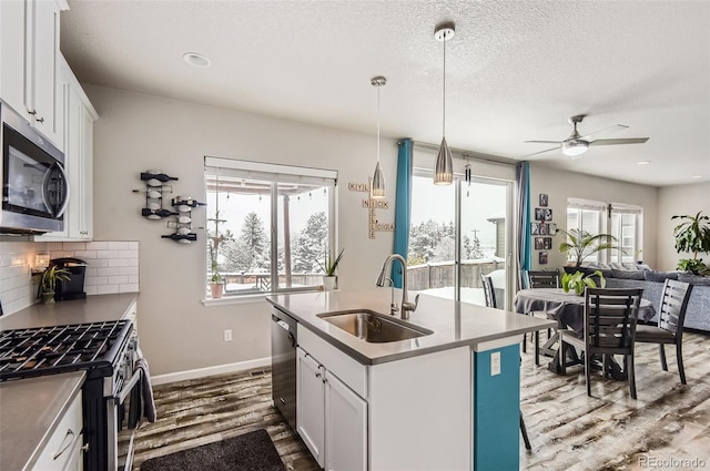 kitchen with a center island with sink, sink, ceiling fan, white cabinetry, and stainless steel appliances