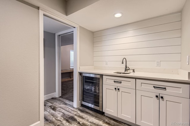 bar featuring white cabinets, hardwood / wood-style flooring, beverage cooler, and sink