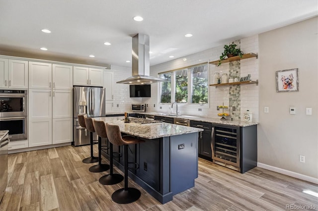 16498 E Lake Dr, Centennial, CO 80016 - kitchen with beverage cooler, stainless steel appliances, island range hood, tasteful backsplash, and light wood-style floors