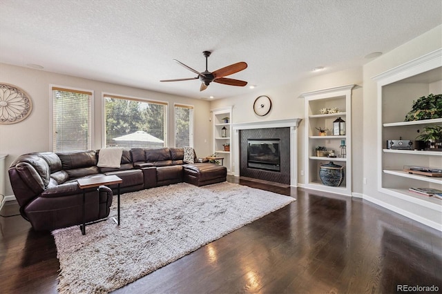 16498 E Lake Dr, Centennial, CO 80016 - living area featuring a textured ceiling, a ceiling fan, built in shelves, dark wood-type flooring, and a glass covered fireplace