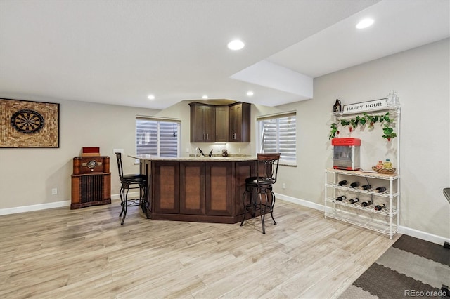 16498 E Lake Dr, Centennial, CO 80016 - kitchen with a kitchen bar, dark brown cabinets, light wood-type flooring, recessed lighting, and light stone countertops