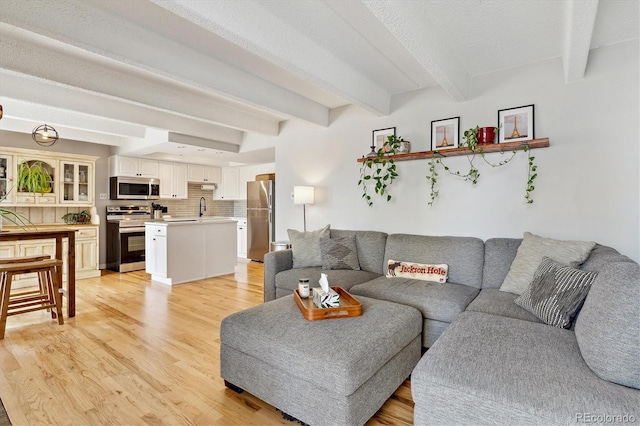 living room featuring beamed ceiling and light wood finished floors