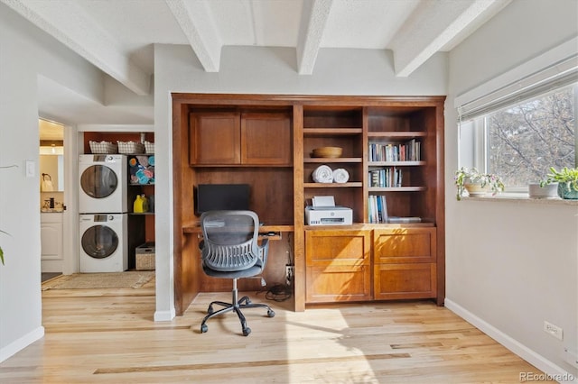 office area with beam ceiling, stacked washing maching and dryer, light wood-type flooring, and baseboards