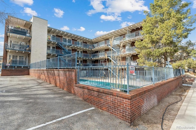 view of property's community featuring fence and uncovered parking