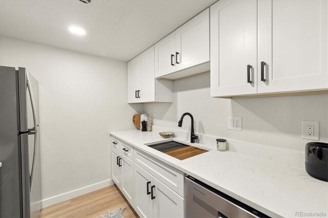 7770 W 38th Ave Unit 108, Wheat Ridge, CO 80033 - kitchen with baseboards, light stone counters, a sink, stainless steel appliances, and white cabinets