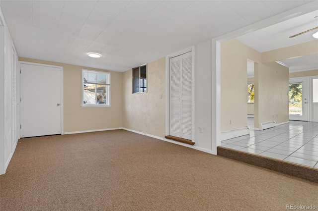 carpeted empty room with a wealth of natural light, ceiling fan, and a baseboard radiator