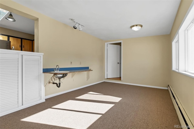 interior space featuring rail lighting, sink, a baseboard heating unit, and dark carpet