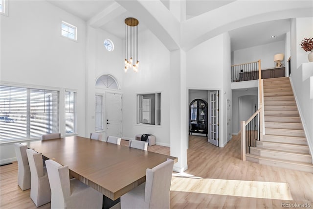 dining space with a towering ceiling, light hardwood / wood-style floors, and a chandelier