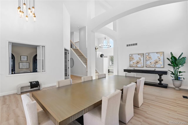 dining space featuring a high ceiling, a notable chandelier, and light hardwood / wood-style floors