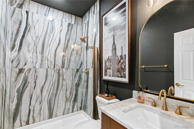 bathroom with a tile shower, vanity, and toilet