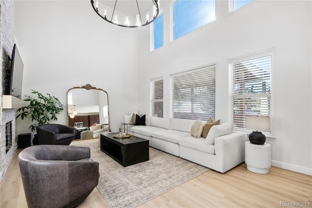 living room with an inviting chandelier, hardwood / wood-style flooring, a large fireplace, and a high ceiling