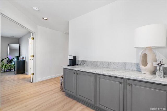 kitchen featuring gray cabinets, light stone countertops, and light hardwood / wood-style flooring