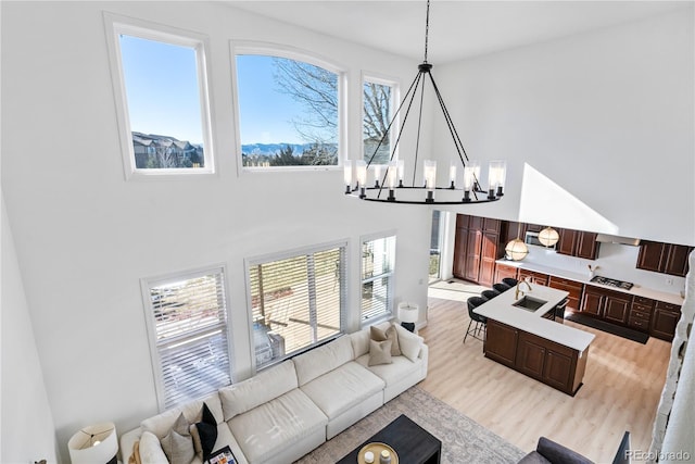 living room with a high ceiling, a chandelier, and light hardwood / wood-style flooring