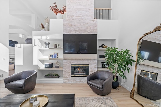 living room featuring a towering ceiling, built in features, and light hardwood / wood-style floors