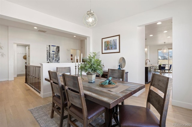 dining area with sink, a chandelier, and light hardwood / wood-style floors