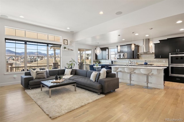 living room featuring a mountain view, sink, a chandelier, and light wood-type flooring