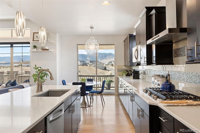 kitchen with hanging light fixtures, a mountain view, sink, and wall chimney exhaust hood