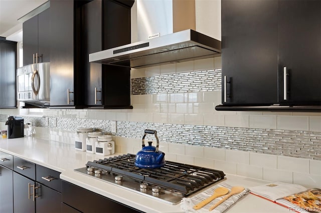 kitchen featuring wall chimney range hood, backsplash, and appliances with stainless steel finishes