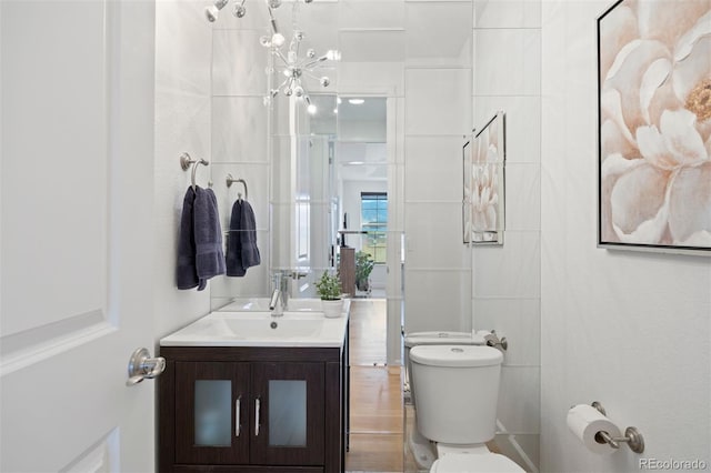 bathroom featuring vanity, tile walls, and toilet