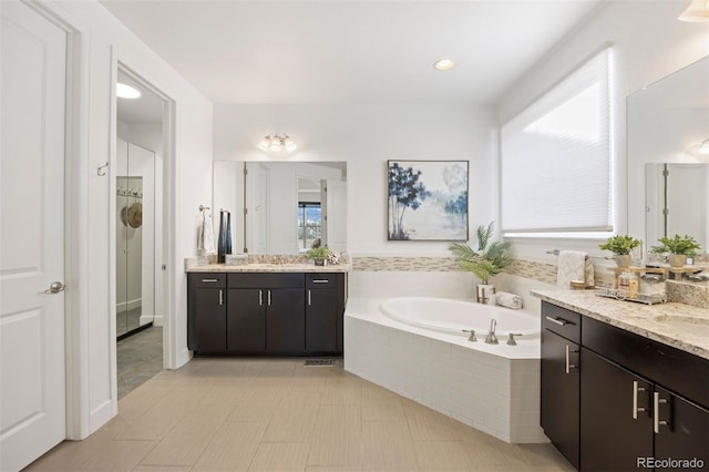 bathroom with vanity and tiled bath