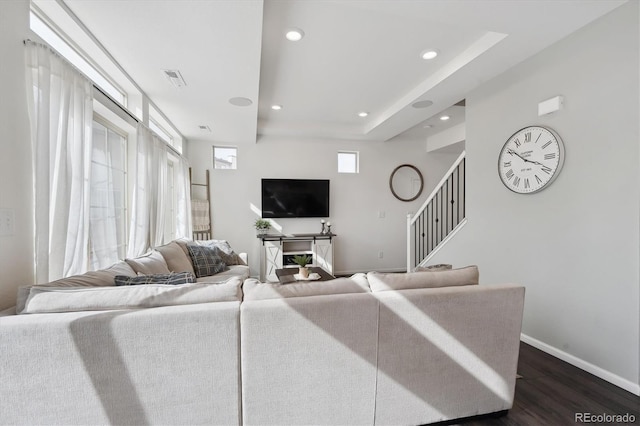 living area featuring baseboards, dark wood finished floors, stairs, a tray ceiling, and recessed lighting