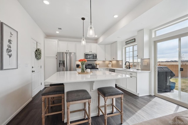 kitchen featuring a sink, a center island, white cabinets, appliances with stainless steel finishes, and decorative backsplash