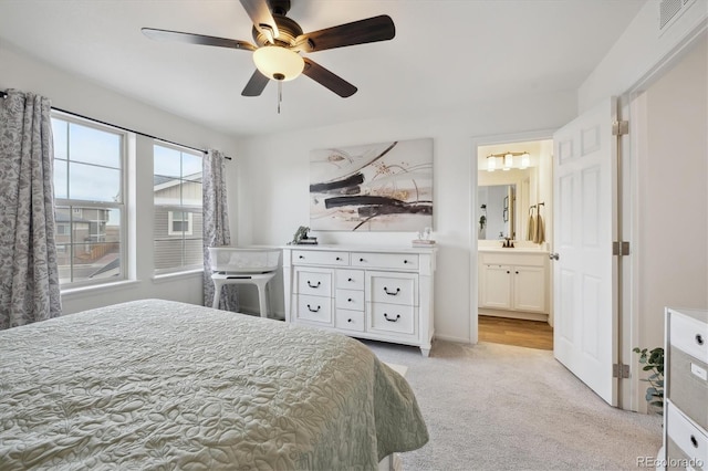 bedroom featuring light colored carpet, visible vents, ceiling fan, a sink, and ensuite bath