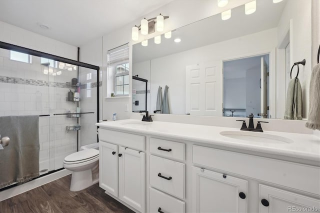 full bath featuring toilet, a shower stall, a sink, and wood finished floors