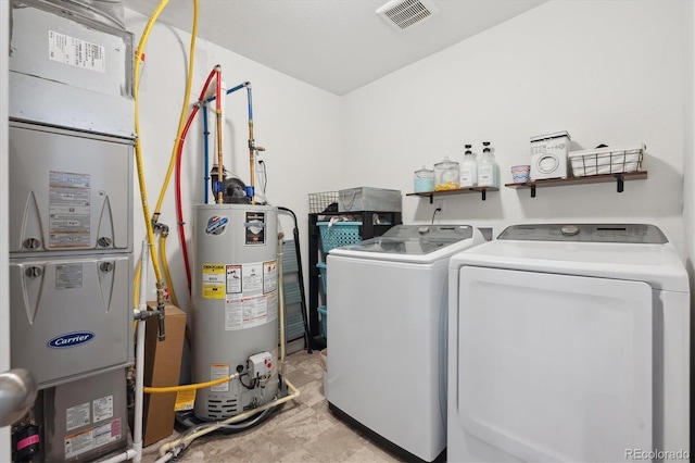 washroom with gas water heater, laundry area, separate washer and dryer, visible vents, and heating unit