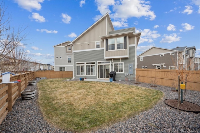 back of house featuring a fenced backyard and a lawn