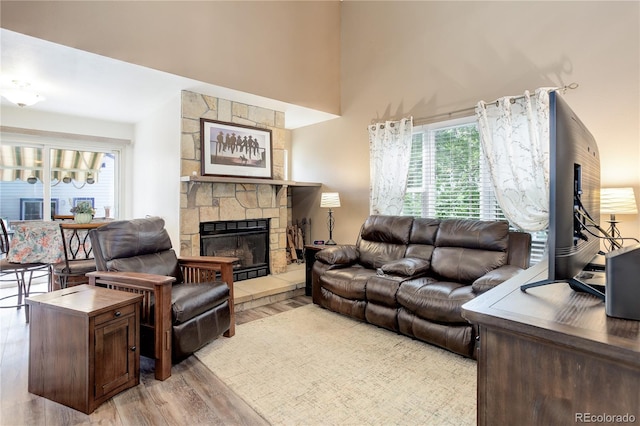 7840 S Windermere Cir, Littleton, CO 80120 - living area featuring a stone fireplace, light wood-type flooring, and a high ceiling