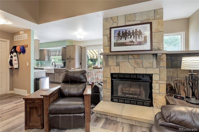 7840 S Windermere Cir, Littleton, CO 80120 - living room with light wood-style floors, plenty of natural light, a stone fireplace, and baseboards