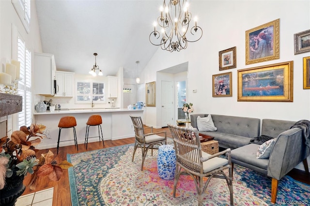 living room with an inviting chandelier, high vaulted ceiling, and light hardwood / wood-style flooring