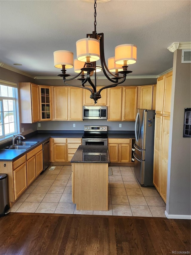 kitchen featuring a center island, ornamental molding, stainless steel appliances, and light wood-type flooring