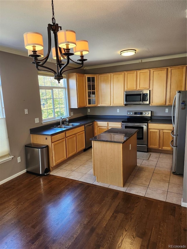 kitchen with stainless steel appliances, sink, pendant lighting, crown molding, and a center island