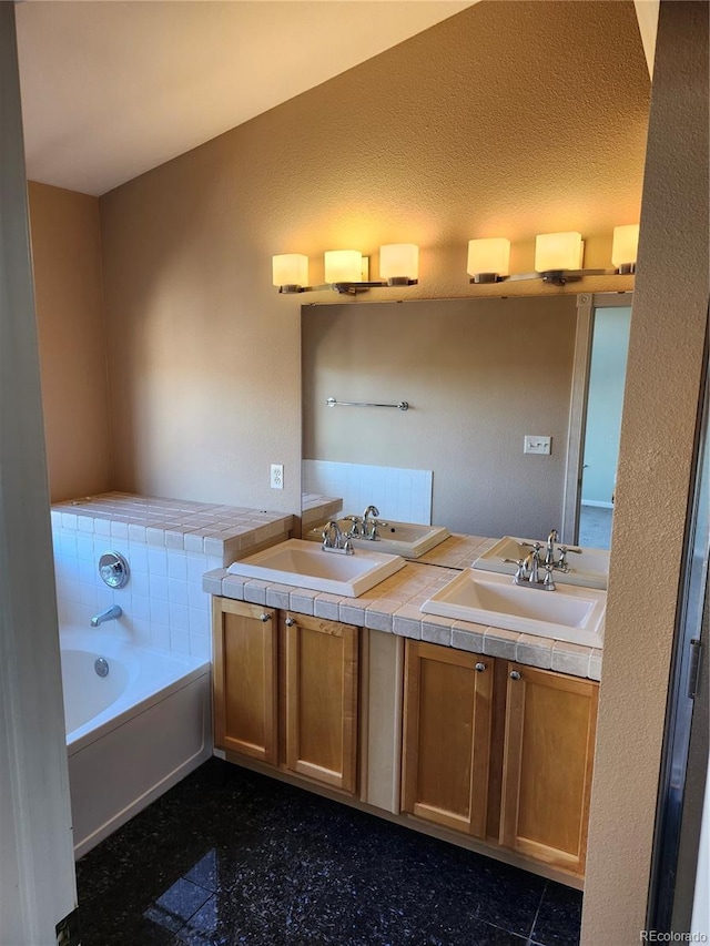 bathroom with vanity, a tub to relax in, and a textured ceiling