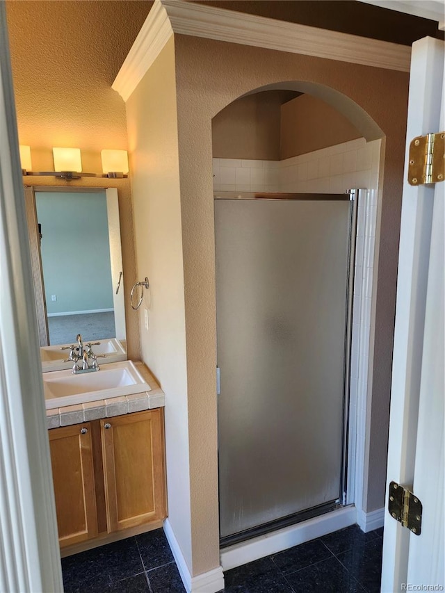 bathroom with vanity, crown molding, a shower with shower door, and a textured ceiling