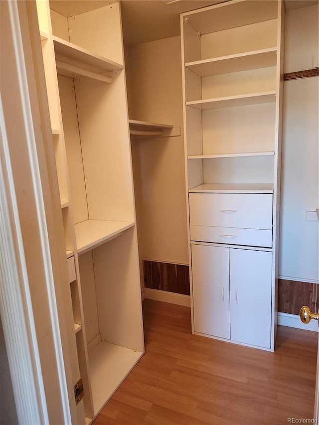 walk in closet with light hardwood / wood-style floors