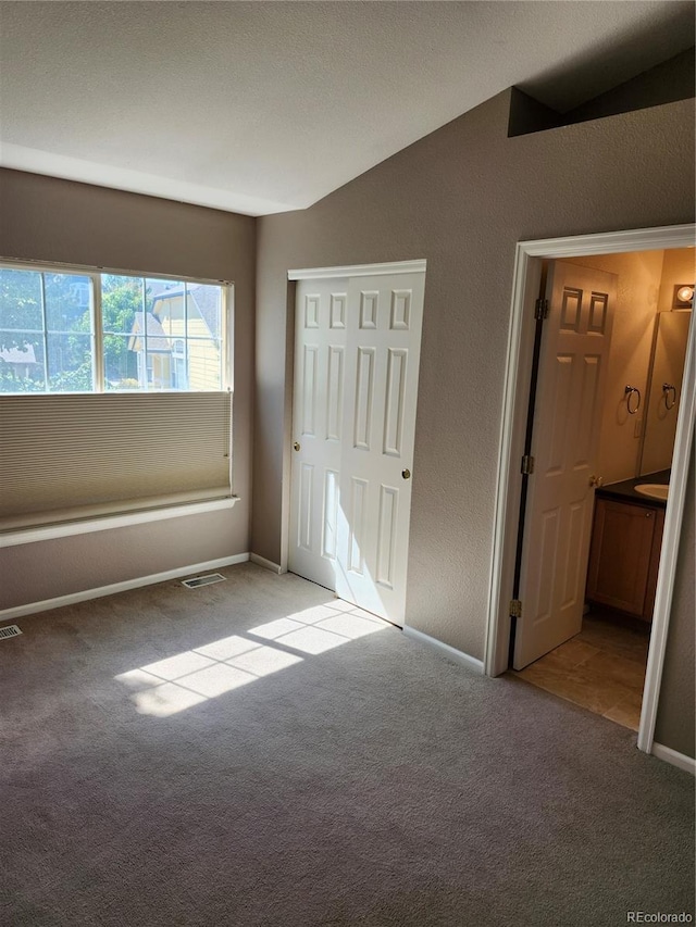 unfurnished bedroom with vaulted ceiling and light carpet