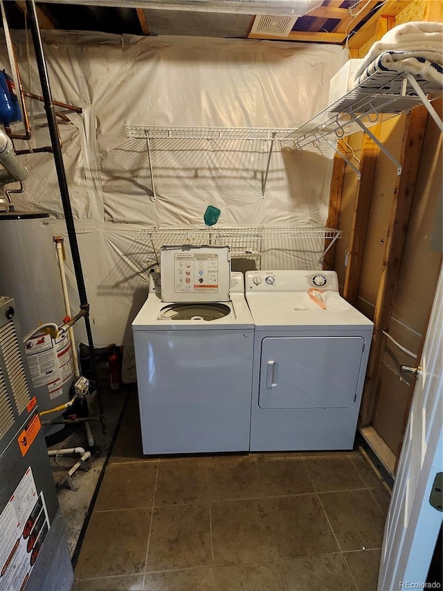 clothes washing area with water heater, separate washer and dryer, and dark tile patterned flooring