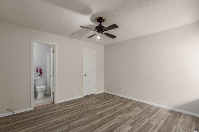 unfurnished bedroom with wood finished floors, a textured ceiling, baseboards, and ensuite bath