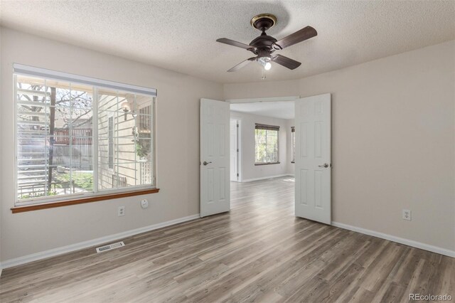 spare room featuring wood finished floors, a textured ceiling, ceiling fan, and baseboards
