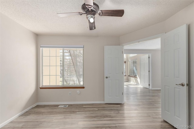 spare room featuring wood finished floors, a textured ceiling, ceiling fan, and baseboards