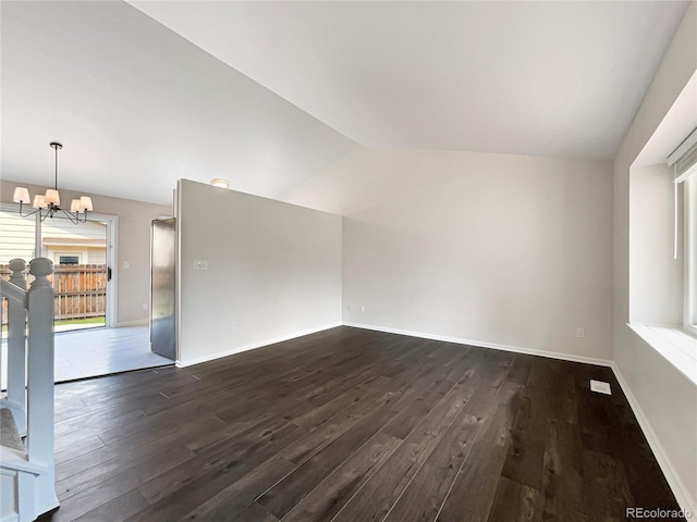 unfurnished living room with plenty of natural light, dark hardwood / wood-style floors, lofted ceiling, and a chandelier